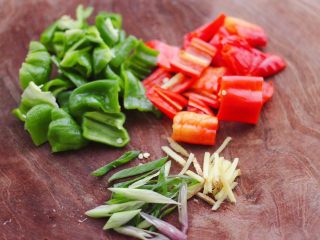 3、双椒辣爆花蟹,用刀把柿子椒和红辣椒切片，葱姜切丝。