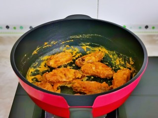 14、蛋黄焗鸡翅,最后加入炸好的鸡翅,翻炒均匀,使每个鸡翅都裹上蛋黄酱即可。