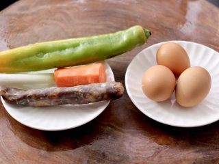 1、腊肠炒鸡蛋,首先备齐食材，腊肠提前蒸熟，胡萝卜洗净去皮。