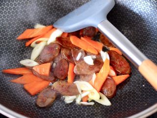 7、腊肠炒鸡蛋,再放入蒜末和胡萝卜，继续小火翻炒片刻。