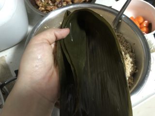 23、蛋黄肉粽,然后再向中间叶脉对折，成一个兜