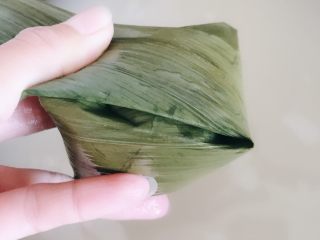11、粽子,包住以后按照这个角的边把粽子叶也折成跟这条边平行。顺势就把粽子叶往下折再沿着粽子的形状这样折下去直到粽子叶都折完，用线把粽子绑起来。