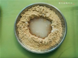 6、香油豆沙馅绿豆糕,在绿豆粉上面挖个小坑，将白糖、凉白开放入；