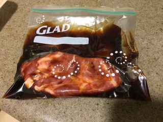 3、中华冷面,拿一个保鲜袋,把猪肩肉放进去,再倒进去酱汁,抓一抓匀,抓紧口子,冰箱冷藏3小时,腌制。