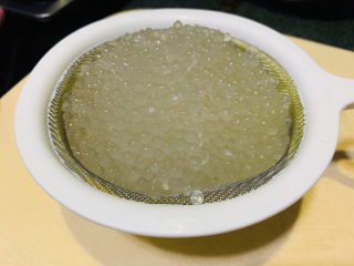 14、芒果西米捞,打开锅盖西米已全部透明,倒掉煮的水,加凉白开水冲下,用捞勺沥干水,西米已经非常晶莹剔透了;