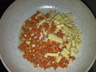 9、三文鱼炒饭,另一个不粘锅加入油，放入胡萝卜丁和玉米粒，摊开后盖盖1-2分钟，直到胡萝卜变软。