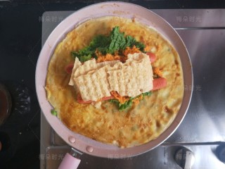 16、煎饼果子,薄脆掰开,放上去。这时候可以关火了。