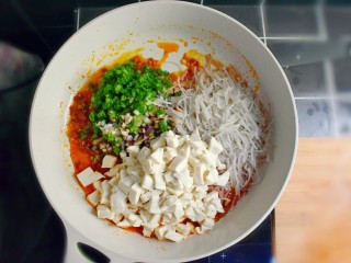 13、麻辣豆腐粉条香菇包,关火，倒入切好的豆腐、葱花、香菇丁、粉条段，并利用锅的余热，翻炒均匀