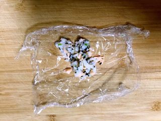 15、三文鱼紫菜饭团,取一块保鲜膜,上面加入一勺三文鱼紫菜拌饭