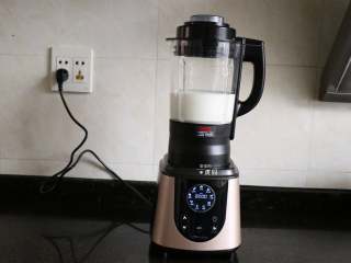 7、花生牛奶,继续倒入水，然后盖上杯盖（事先已将投料盖压紧在杯盖上），再将杯盖顺时针旋转与杯体扣好，接通电源；