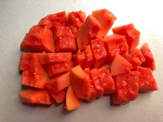 2、木瓜奶昔,首先把木瓜清洗干净,对半切开,把里面的籽掏干净,用刀把皮削点,再切成小块待用。