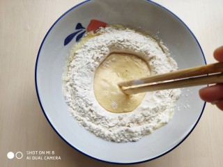 6、茴香小油条（不用手揉）,倒入面粉，用筷子从中间往外将蛋液和面粉混合成面糊。