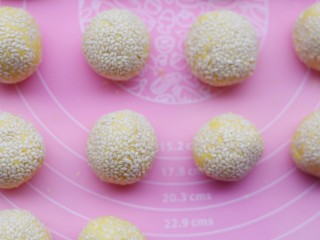8、烤箱低油版奶香烤南瓜芝麻饼,每一个圆球表面裹上白芝麻,将芝麻往里按一按。