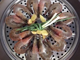 7、清蒸大虾,把虾摆在蒸屉上，放上姜片、葱结，开大火蒸6分钟即可。