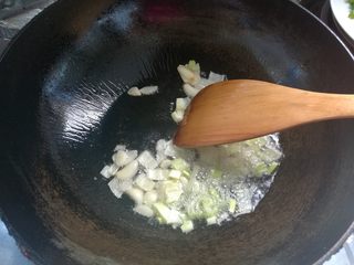 6、素味炒饼,放入葱碎、蒜片爆香。