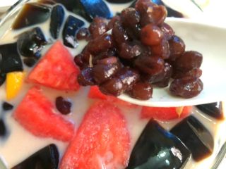 6、黑凉粉水果捞,加入黑凉粉,再加入芒果和西瓜,再放上蜜红豆,加入几块冰块即可。