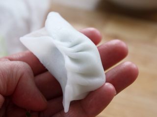 7、水晶虾饺,14.从一头往另一头折，并且只折后面。左手食指将后面面皮往前推送，右手食指接住，与前面面皮捏在一起。