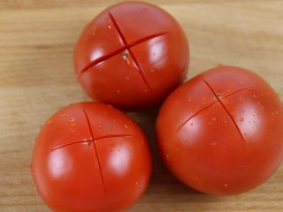 2、番茄金蛋烧,番茄洗干净，底部轻轻划十字刀。