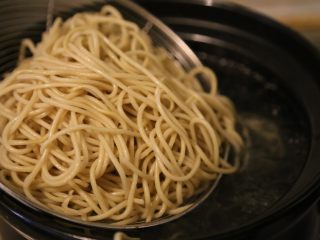 9、武汉热干面,烧一锅水,水开后,将面条放入沥网中,放入水中上下焯烫,约20秒。