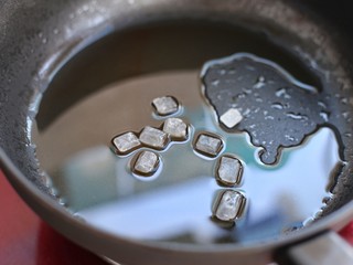 6、排骨焖饭,锅中倒适量食用油烧至五成热，放入冰糖小火翻炒至冰糖融化