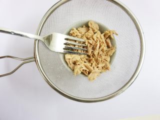 3、芝士片烤吞拿鱼饭团,用叉子将吞拿鱼里的油水挤掉,备用。