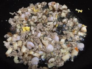 6、海鲜菠萝饭,把肉末，香菇，蒜蓉，虾仁和鱿鱼丁一起放入锅内放油和蒜蓉一起爆炒 ，放稍许盐