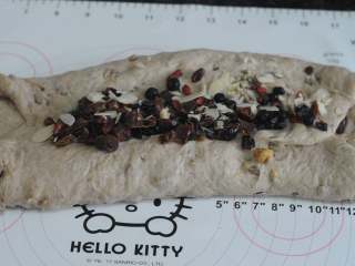 8、圣诞史多伦,将面片折三次，第三次的面片边缘放在面团的中间，接口处撒上余下的果敢和杏仁片。再用擀面杖将果干压实，总之要把远离阿里的果干全部都放进去。