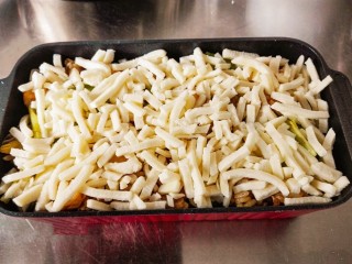 7、什锦咖喱焗饭,把炒好的米饭铺在容器中。在米饭上面。铺上一层奶酪丝。一定要铺均匀。