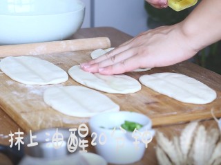 6、陕西油泼面,然后将面团揉成条状，擀成椭圆面皮，中间压一道，抹上食用油，醒发20分钟