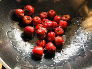 11、山楂球,稍微冷却1分钟左右，倒入山楂翻炒均匀，刚开始炒的时候冰糖可以拉丝，颜色为透明色，这是正常现象。