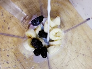 4、果粒奶昔【香蕉桑葚+香蕉芒果】,把香蕉和桑葚放入榨汁机,倒入牛奶。