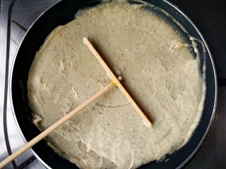 5、杂粮煎饼,用煎饼推子围中心打圈绕圆，把面糊在锅中推开摊平，中小火加热。（薄厚根据个人喜好）
