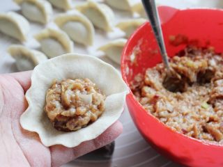 9、十味 多汁猪肉煎饺,将饧好的面团搓成长条,揪成小剂。取一个小剂子,按扁,擀成中间厚,周边薄的皮,舀一坨馅料在饺皮中。