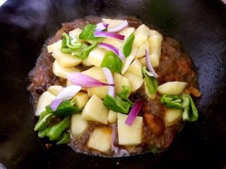 5、大盘鸡的做法及吃时注意事项,中火煮一会后加入土豆余下的洋葱几片青椒，盖上锅盖，中小火慢炖。