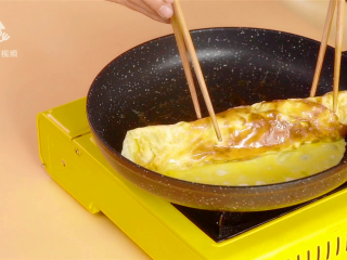 14、春游赏花便当,手残党也能轻松搞定,倒第二碗蛋液,旋转平底锅摊平,并接触到一旁的蛋卷,蛋液凝固后,叠成蛋卷