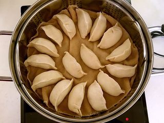 25、东北酸菜饺子,把包好的蒸饺放入笼屉，冷水上屉，放入蒸锅