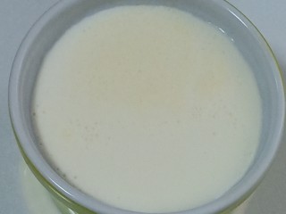 10、红豆双皮奶,过筛厚的牛奶再缓缓的沿着蒸器的边缘倒入。奶皮就会浮在上面了，如图。