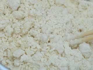 2、糯米烧卖,将开水缓慢倒入面粉,一边倒一边用筷子搅拌,直至成絮状。