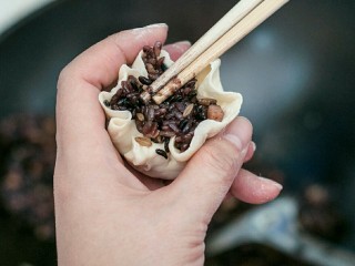 9、糯米烧卖,将糯米饭放入面皮,用筷子压实一下,靠近收口处捏紧,口不要完全封住。