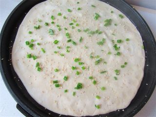 7、老妈酱香鸡蛋单饼卷,上面一层喷上少许水，再均匀洒上白芝麻，并用锅铲压一压，让芝麻蘸如面里。再均匀撒上葱花，盖上锅盖烙至微微金黄色