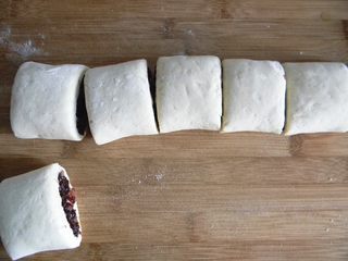 8、腊肉糯米卷,把做好的生胚移到一个木质案板上，手起刀落，高抬刀快速把面卷切小段，这样面卷的的切口才整齐不塌陷