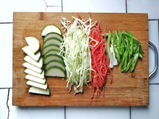 2、月半弯炒(拌)面,青椒、青葱白斜切成段;胡萝卜、卷心菜切丝;青南瓜切至4-5毫米片(青南瓜较柔弱,切丝易断,稍有厚度,熟后食时,非常柔软,可以增加并丰富整个菜的口感)