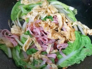 8、火腿鸡蛋炒面,再放入火腿丝和鸡蛋皮,加少许盐翻炒均匀;