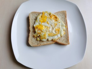 4、芝士火腿三明治,煎熟的鸡蛋放到面包片上。
