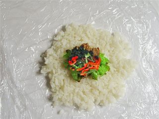 2、可爱的企鹅饭团,在双层保鲜膜上铺好米饭放上家常菜做馅儿，不要放得太多，饭团不容易团起来