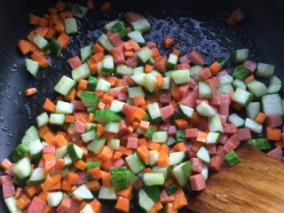 3、美味三色炒面#面条变身计划#,锅烧热，倒入适量的食用油，然后把黄瓜丁，胡萝卜丁，火腿肠丁倒入翻炒片刻。