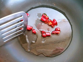 6、蒜苔炒螺丝肉（香辣版）,接着把切好的干辣椒下锅，开小火把干辣椒煸炒至枣红色