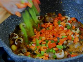 6、来一份下饭又下酒的酱爆香螺，勾住吃货们的胃,倒入料酒，撒入盐、糖、青红辣椒丁继续翻炒。