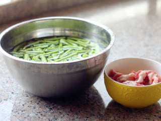 5、蒸卤面,蒸面条的空档，把五花肉片加料酒、淀粉和大葱腌制一会儿，豆角摘干净，切成段，用盐水泡一下。