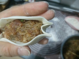 18、肉沫粉丝包,左手拖住。右手在顶端往里戳进去一点,然后捏住。